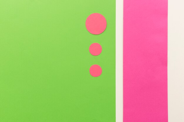 Pink circle shape papers in different sizes arranged on green card paper