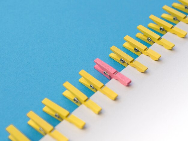 pink clothespin surrounded by yellow ones