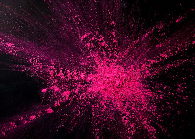 Pink color powder splashing over black backdrop