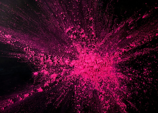 Pink color powder splashing over black backdrop