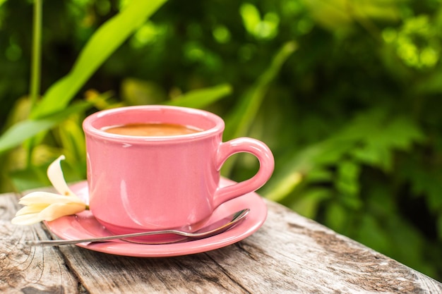 Pink cup of coffee on wooden table