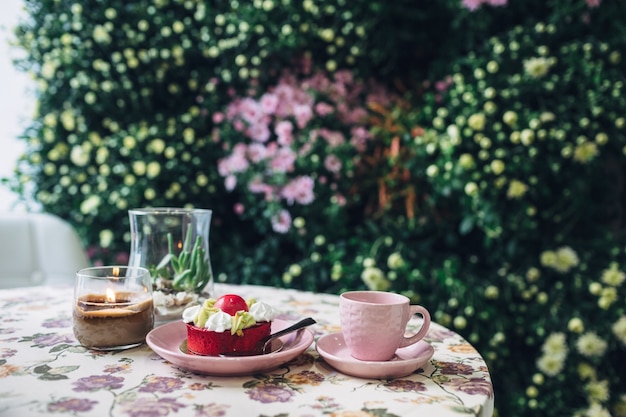 Tazza rosa e piastra con torta si trova sulla tavola rotonda prima della parete w