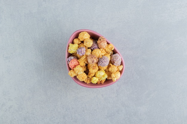 A pink deep plate of sweet multicolored popcorn .  