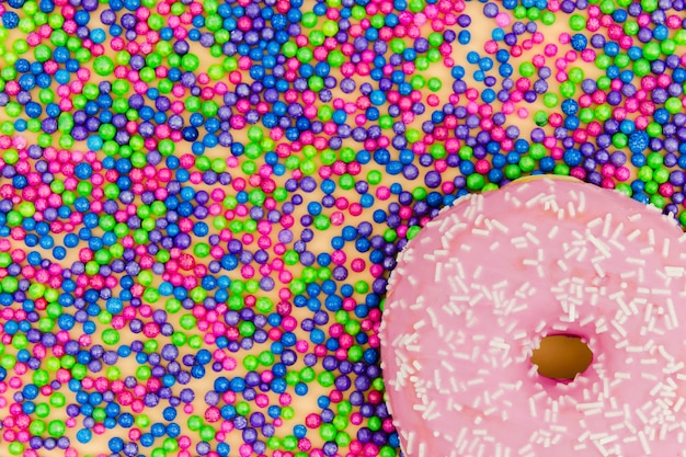 Pink donut on sprinkles ball background
