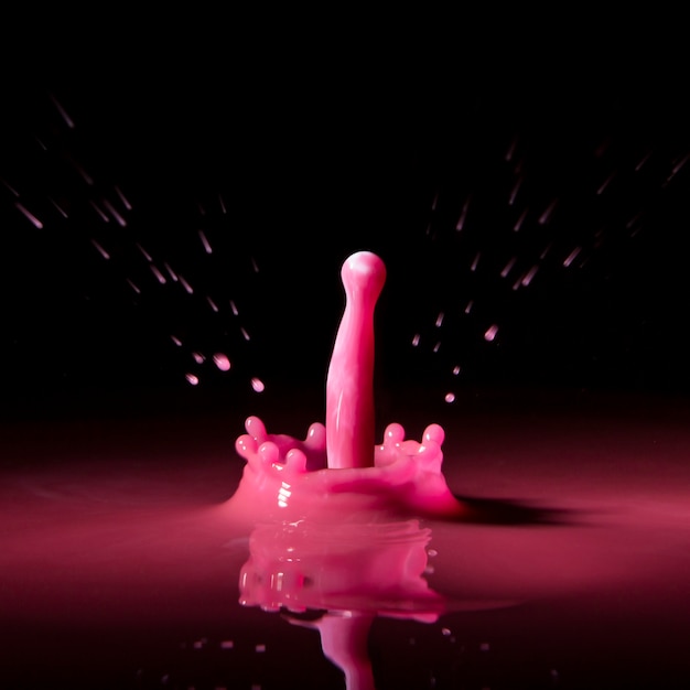 Pink drop splashing on black