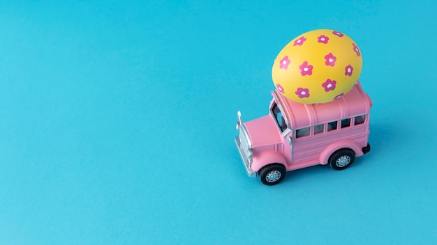 Free photo pink easter car with floral yellow egg still life