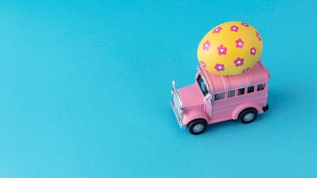 Pink easter car with floral yellow egg still life