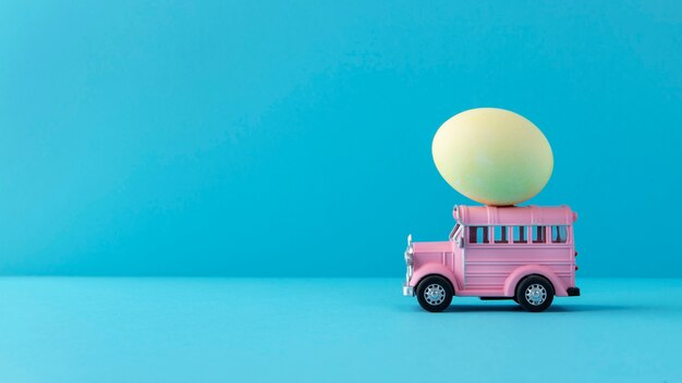 Розовый пасхальный автомобиль с натюрмортом из желтого яйца