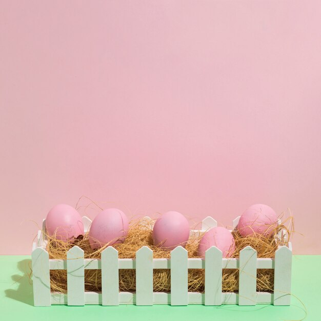 Pink Easter eggs on hay on green table