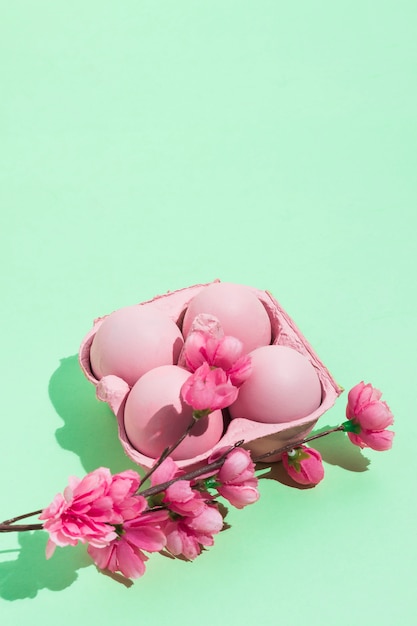 緑色のテーブル上の花が付いている棚のピンクのイースターエッグ
