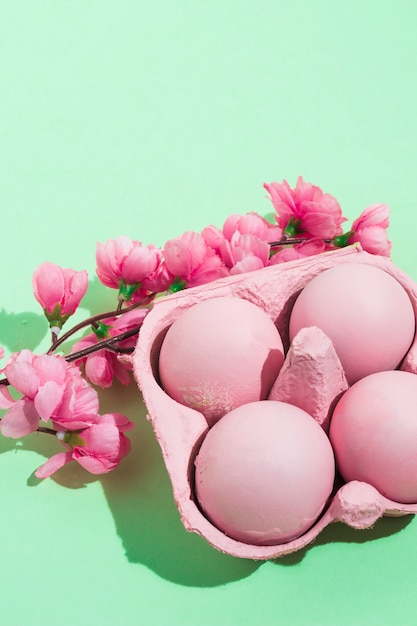 Pink Easter eggs in rack with flowers on table