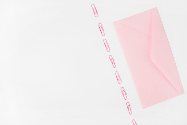 흰색 바탕에 분홍색 봉투와 종이 클립
