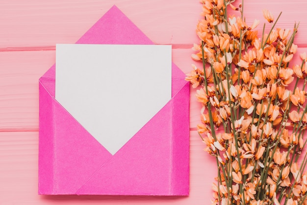 Free photo pink envelope with blank paper and floral decoration