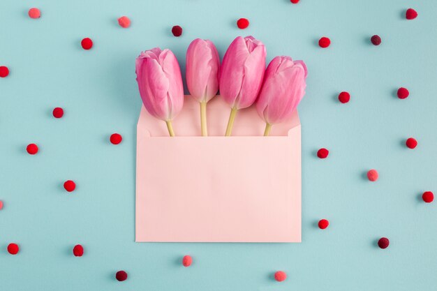 Розовые цветы в конверте среди мягких конфетти