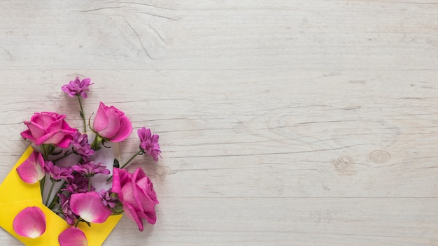 Pink flowers in envelope on wooden table