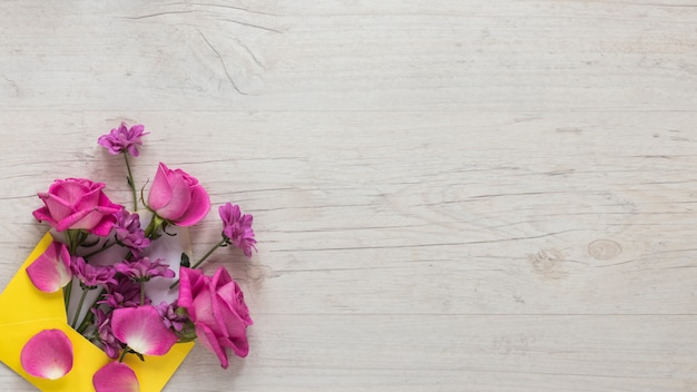 木製のテーブルの上の封筒にピンクの花