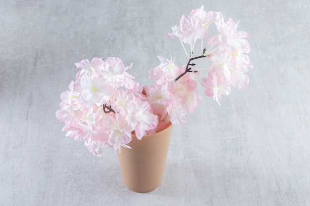 白い背景の上に、花瓶のピンクの花。