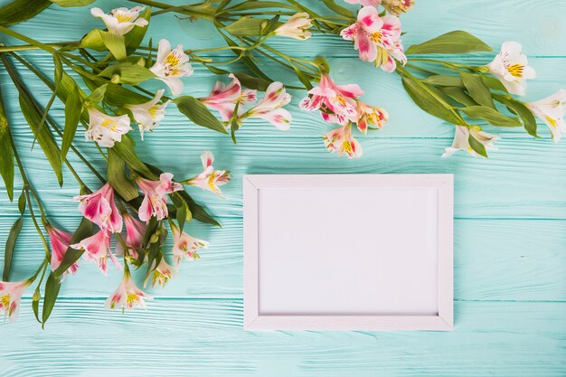 Pink flowers with blank frame on table