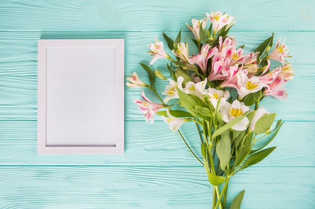 Pink flowers with blank frame on wooden table