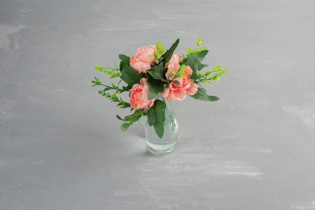 Pink flowers with green leaves in a glass vase.