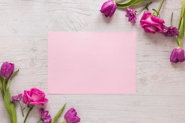Pink flowers with paper on wooden table