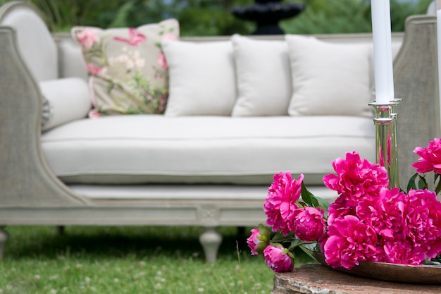 Розовые цветы с белым диваном фоне