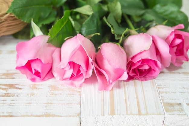 白い木製の背景にピンクの新鮮なバラ