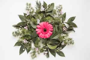 Free photo pink gerbera flower with plant branches on table