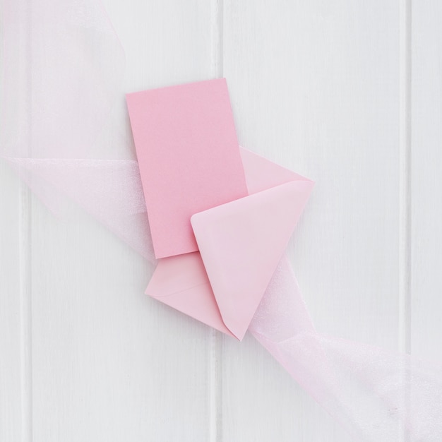 흰색 나무 배경에 봉투와 핑크 인사말 카드