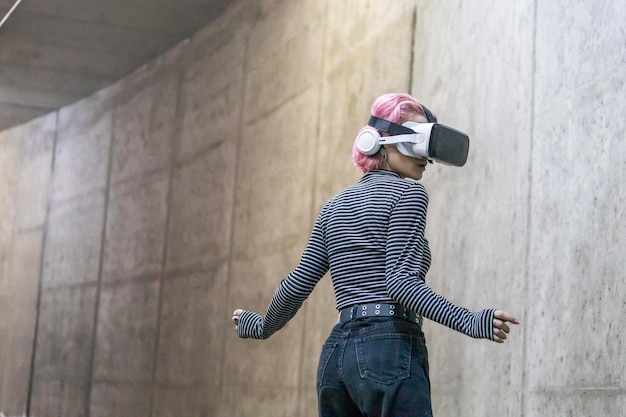 Девушка с розовыми волосами носит комплект Vr и стоит в туннеле