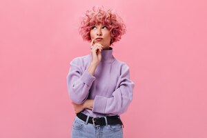 pink-haired woman looks thoughtfully on isolated wall