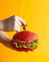 Free photo pink hamburger a woman holding burger with beef patty tomato lettuce leaf sauce and olive