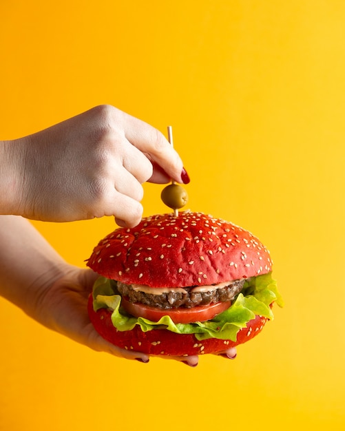 pink hamburger a woman holding burger with beef patty tomato lettuce leaf sauce and olive