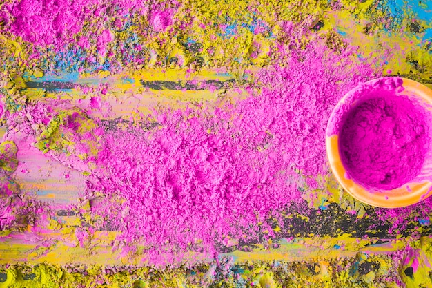 Pink holi powder in bowl on wooden background