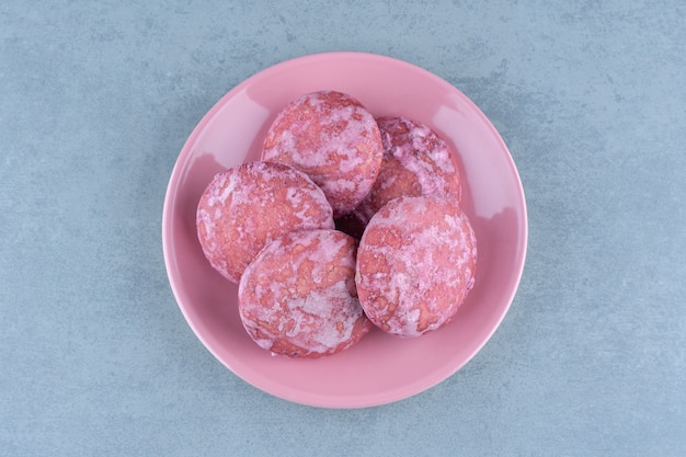 Розовое домашнее печенье на розовой тарелке.