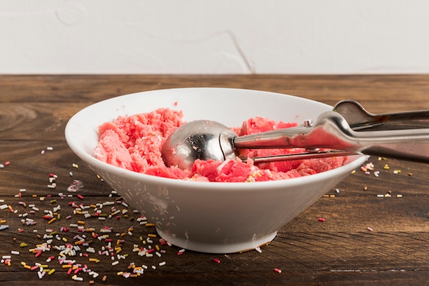 Pink ice cream in bowl and sprinkles