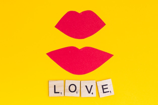 Pink lips kiss with phrase love on bright background