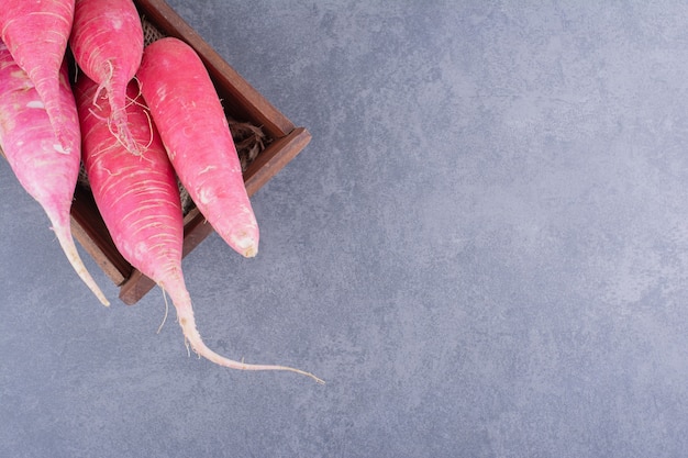 Free photo pink long radishes isolated on concrete surface