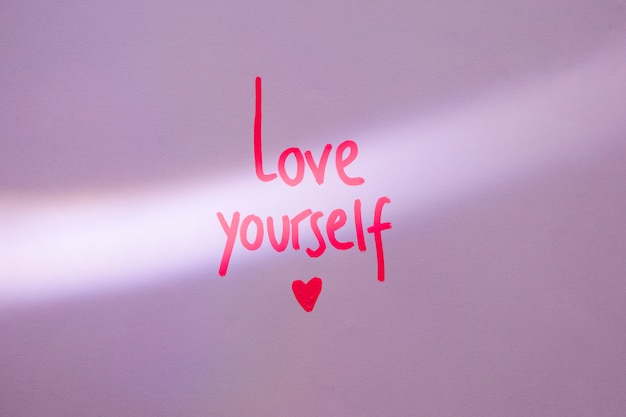 Free photo pink love yourself inscription on purple table