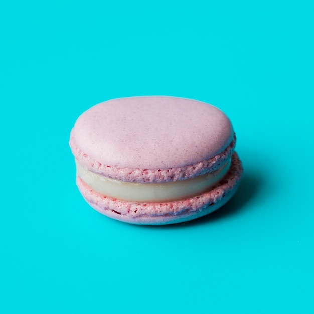Pink macaroon with cream on blue background