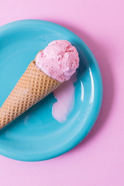 Pink melted ice cream on blue plate flat lay
