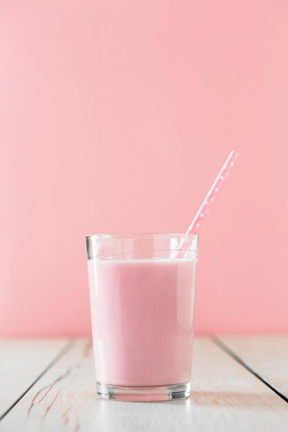 Розовый молочный коктейль в стакане с соломой