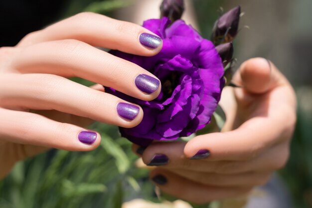 Pink nail design. Female hand with pink manicure holding eustoma flower