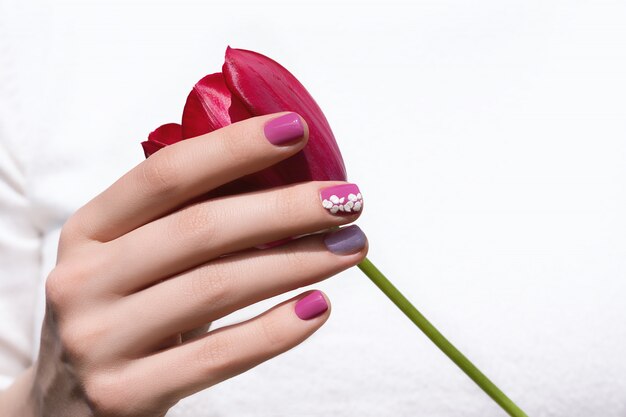 핑크 네일 디자인. 튤립 꽃을 들고 분홍색 매니큐어와 여성 손