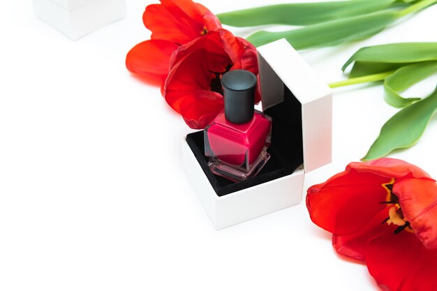 Pink nail polish bottle and tulip flowers on white background