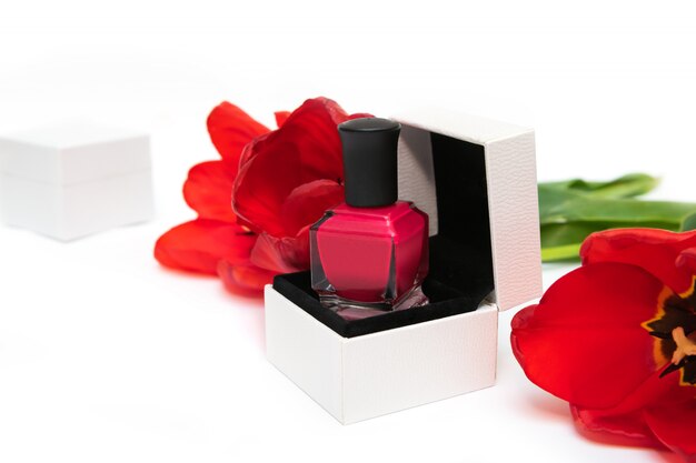 Pink nail polish bottles and tulip flowers on white background