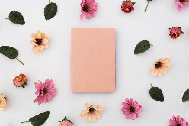 pink notebook with pattern of flowers around on white background