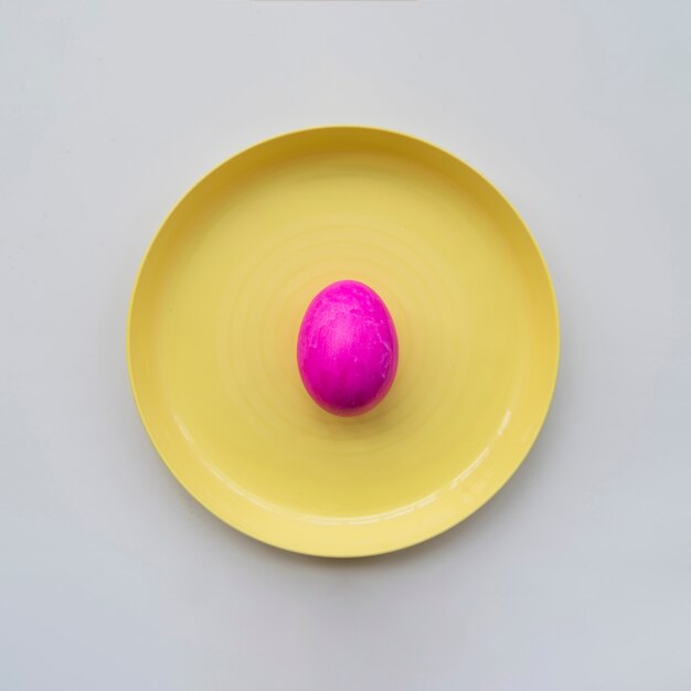 Розовое расписное яйцо на тарелке