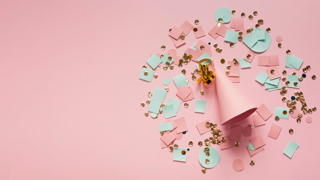 Pink party hat surrounded by confetti and paper