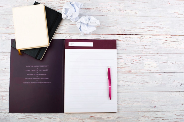 Free Photo pink pen lies on white notebook on white floor